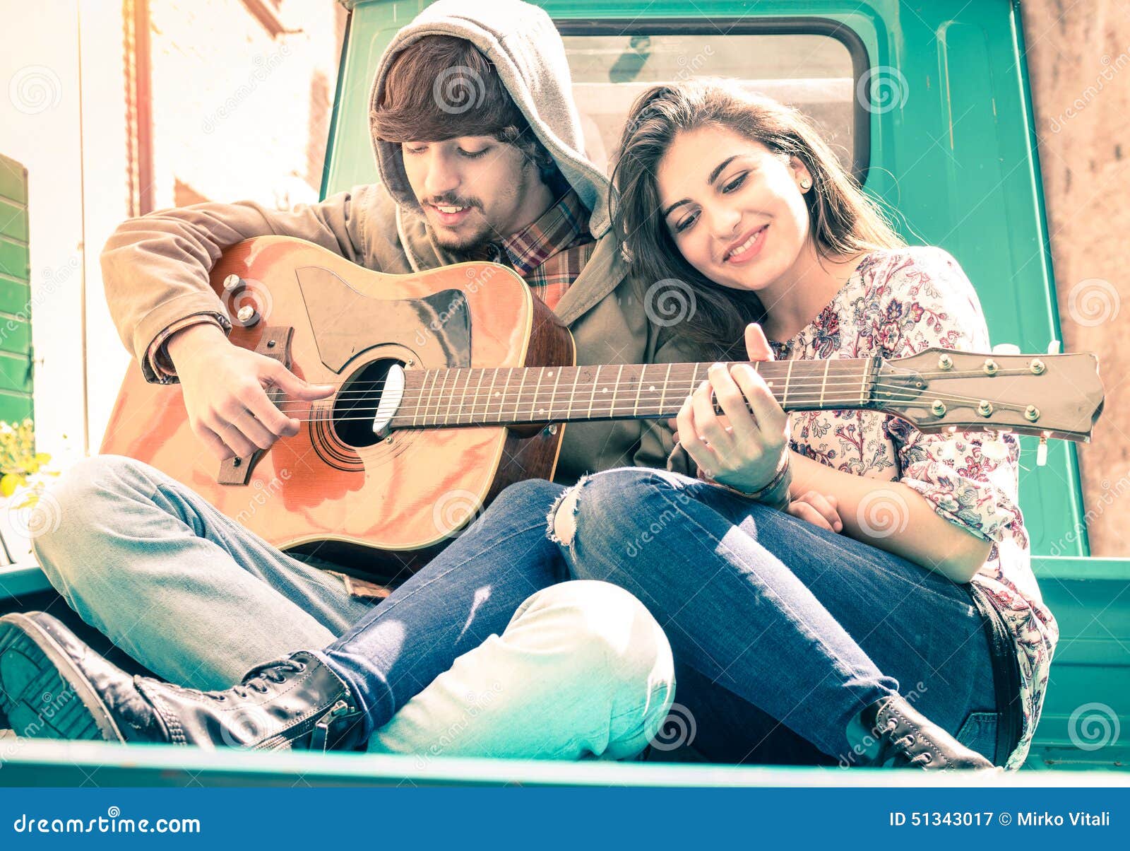 romantic couple of lovers playing guitar on vintage minicar