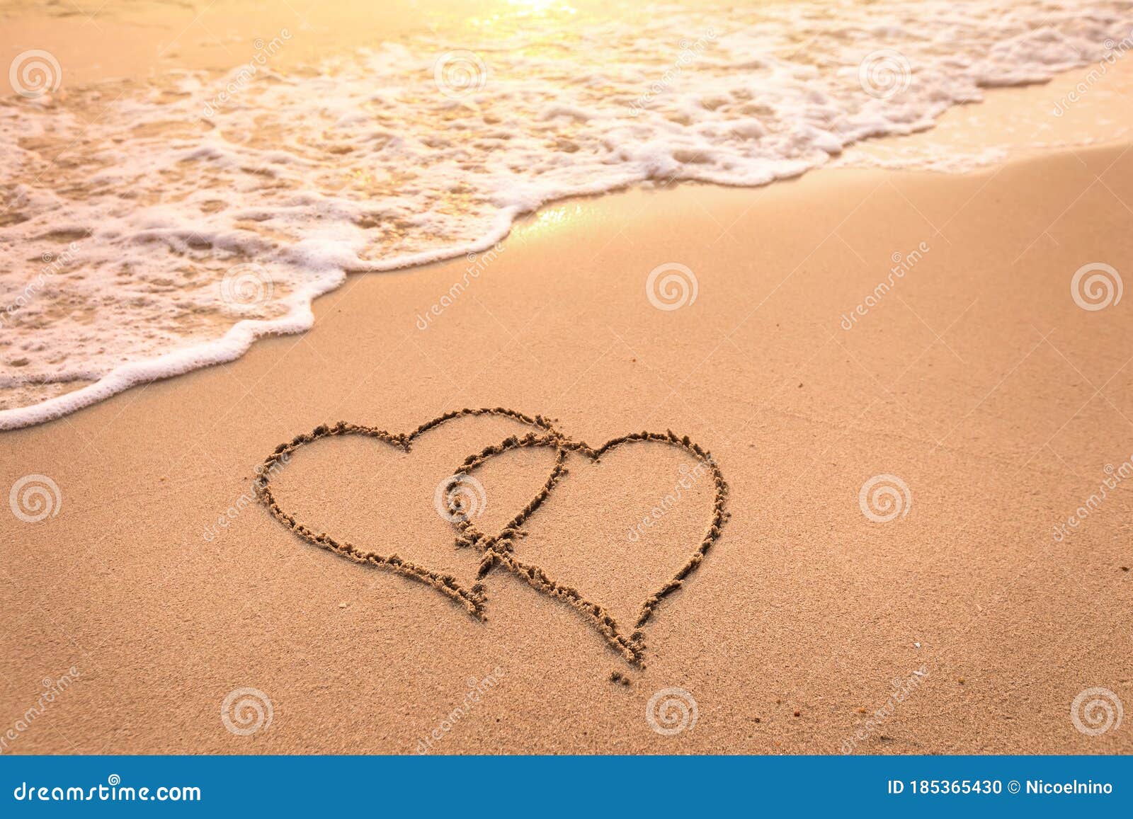 romantic honeymoon holiday or valentine`s day on the beach concept with two hearts drawn on the sand, tropical getaway for couple
