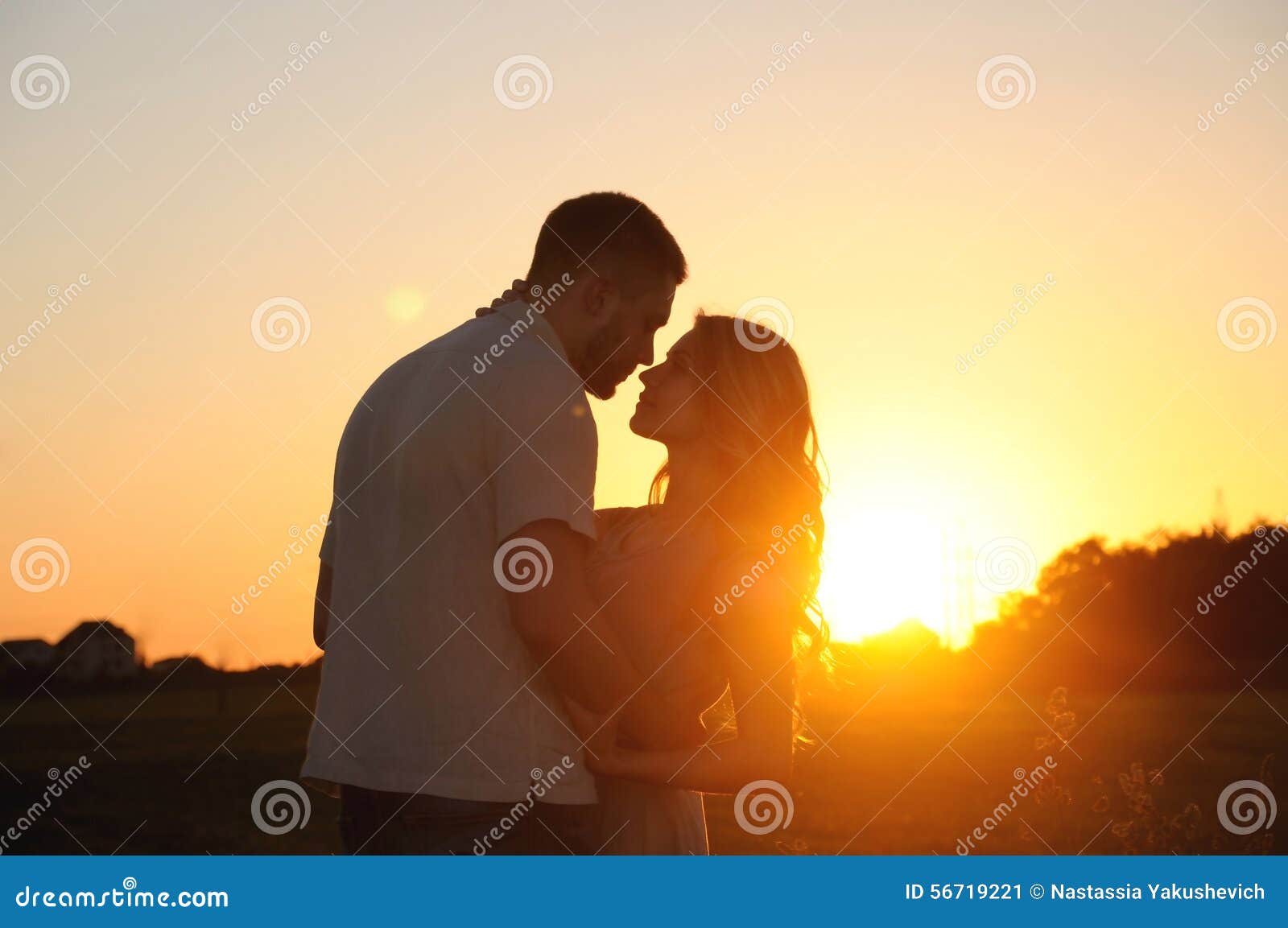 romantic sensual young couple in love posing in field at the sun