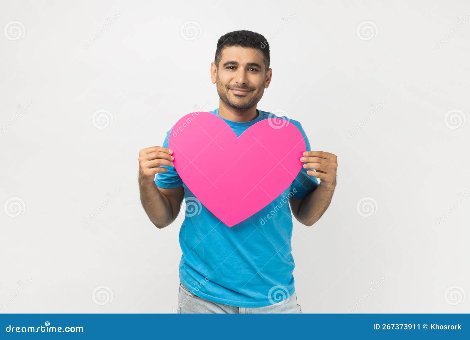 romantic smiling joyful man standing holding big pink heart, expressing fondness and love.