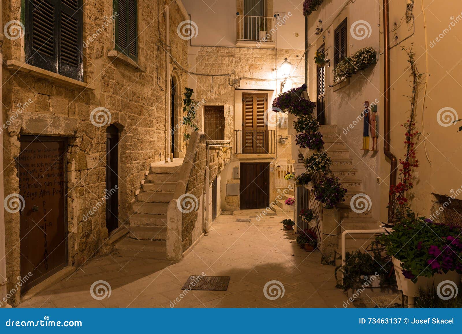 romantic streets of polignano a mare old town by night with poems written on stairs, apulia region, south of italy