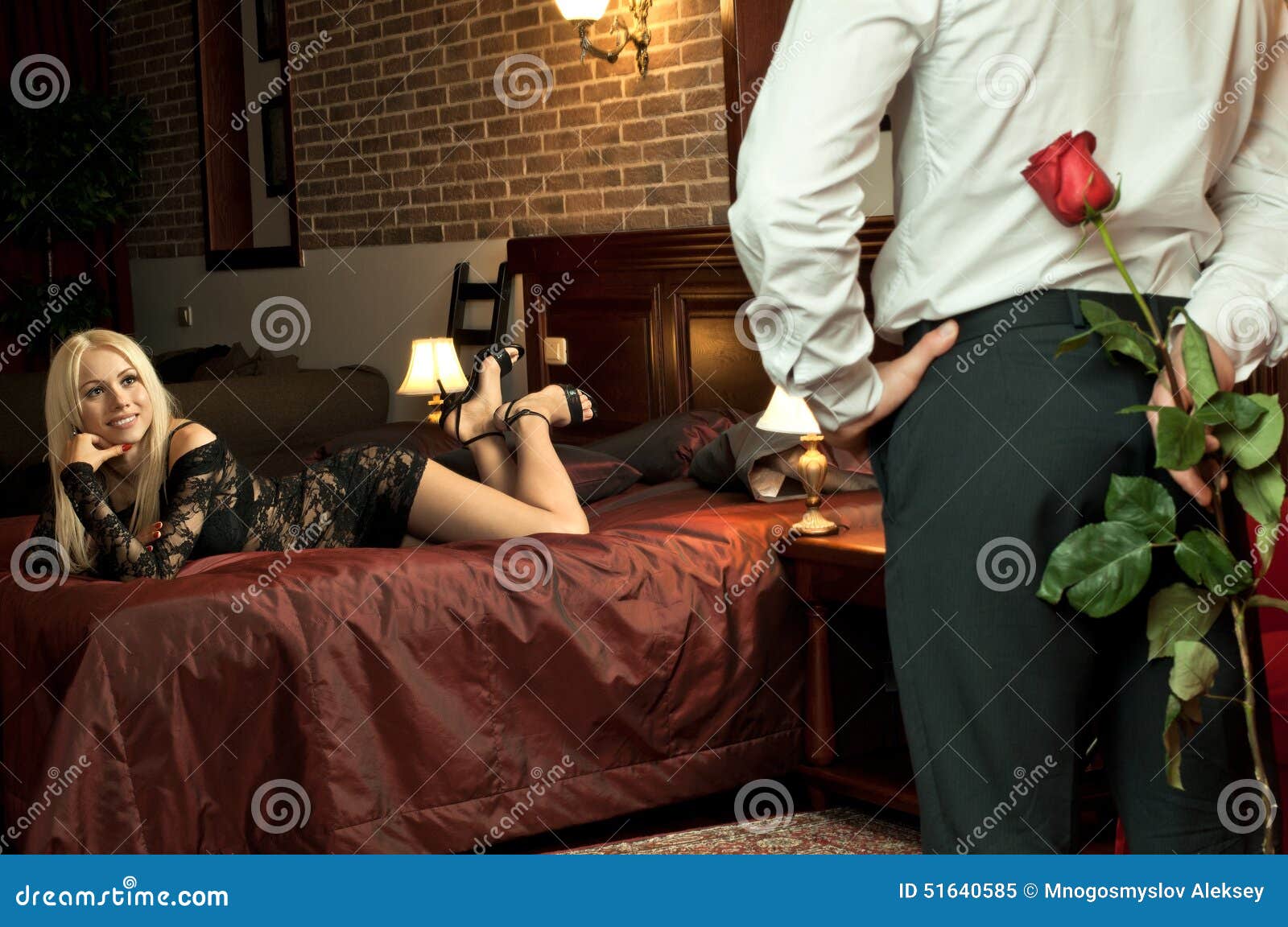 Romantisches Datum. Romantisches Abenddatum im Hotelzimmer, Kerl mit sexy Mädchen auf Bett