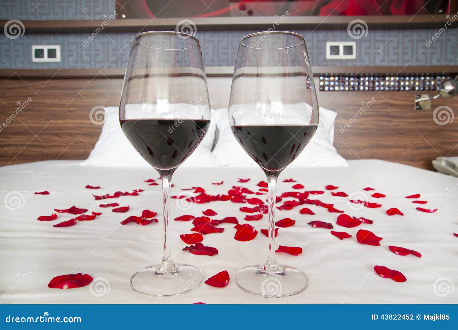 Romantiskt sovrum exponeringsglas av rött vin och rosa kronblad ...