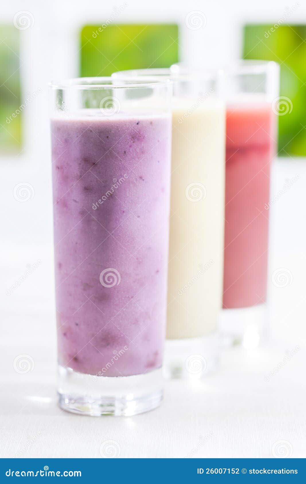 Romige yoghurtbes smoothie. Een lang glas van romige gemengde yoghurtbes smoothie met een verscheidenheid van andere aroma's in een achteruitgaande rij met ondiepe dof