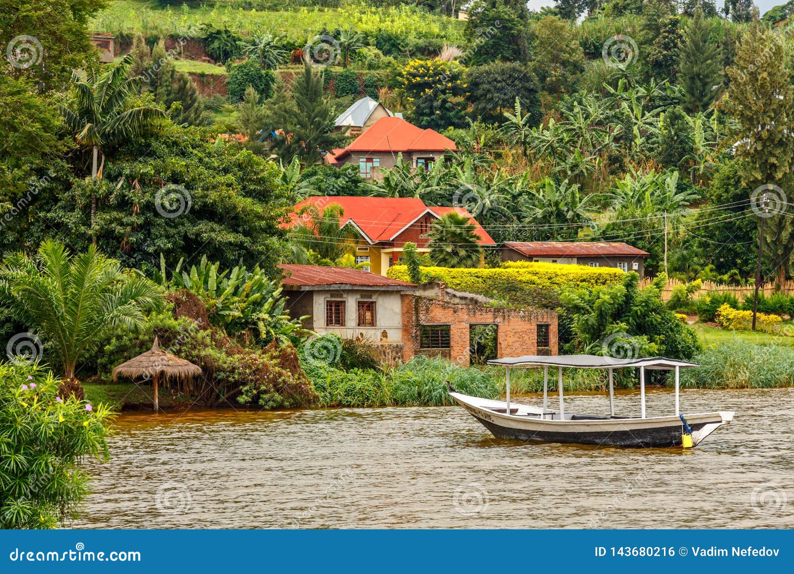 roof boat anchored at the coast with rwandan village in the background, kivu lake, rwanda