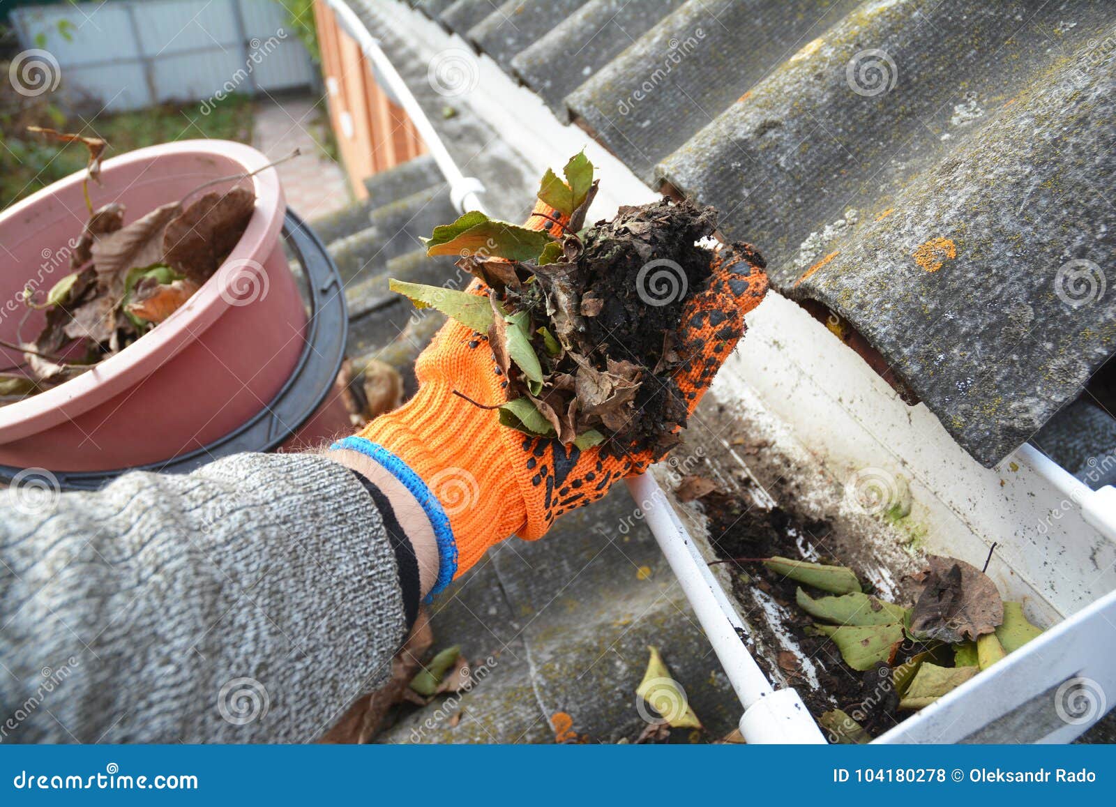 roof gutter cleaning from leaves in autumn with hand. roof gutter cleaning tips.