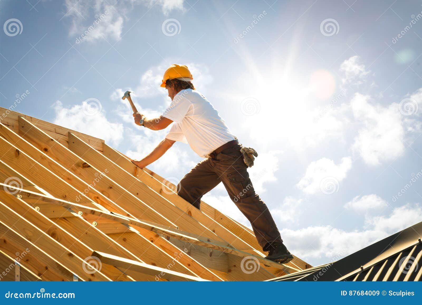 roofer carpenter working on roof on construction site