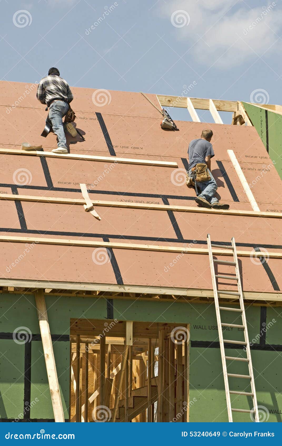 Roofers Roof New Home Revised. Workers put a new roof on a new home under a slightly cloudy sky.