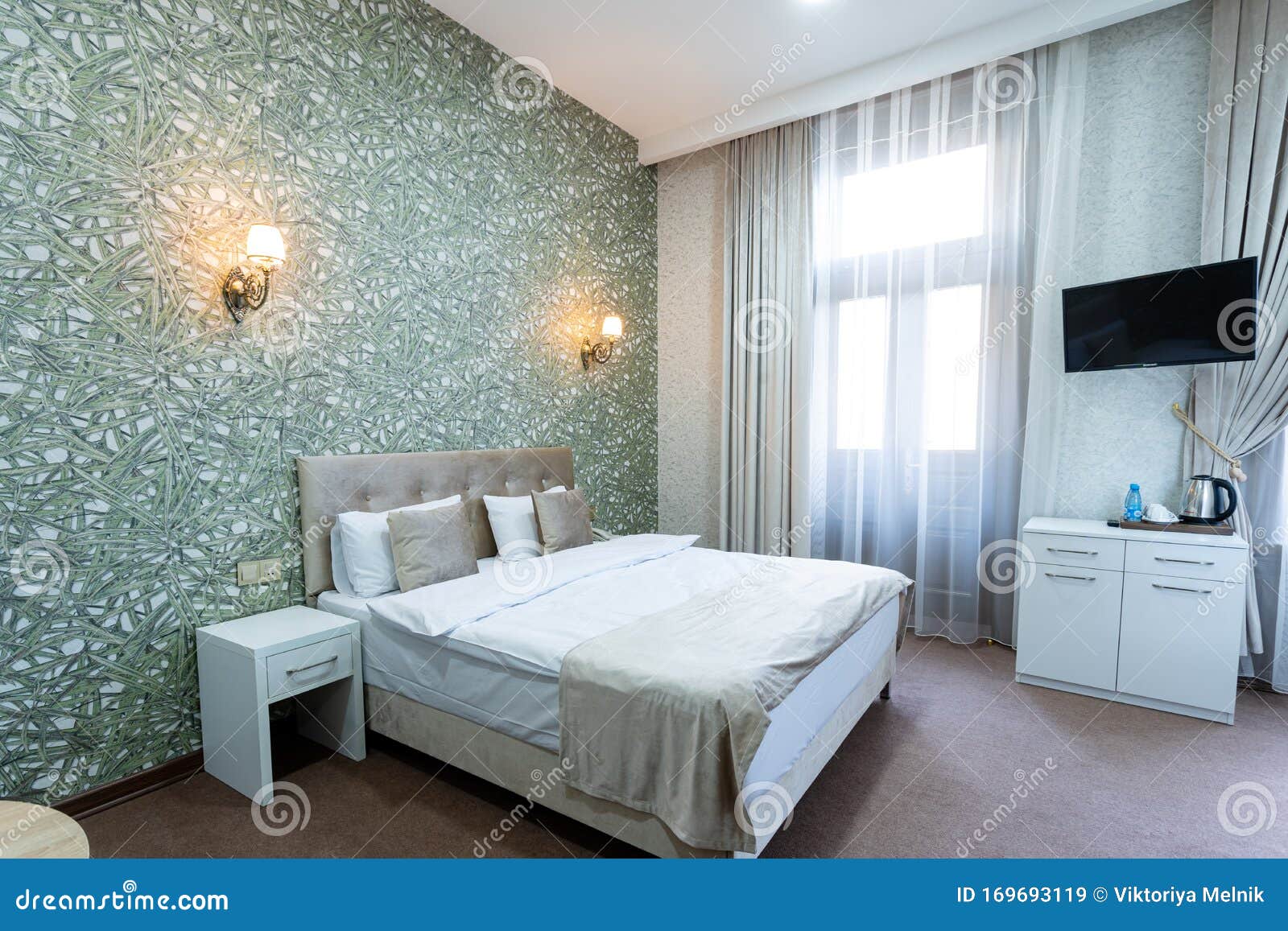 A Room with a Double Bed, a White Nightstand, a Table at the Side of