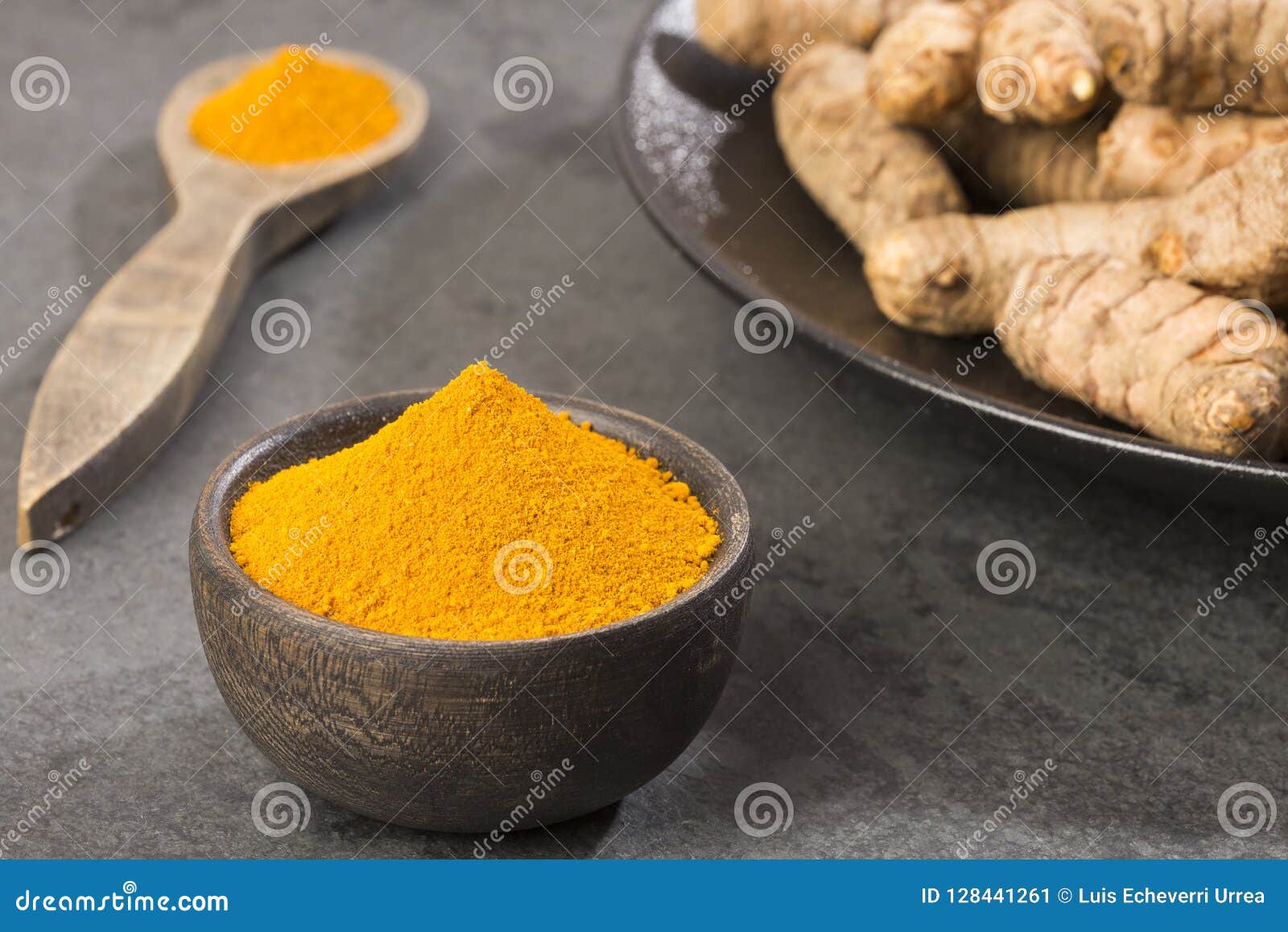 turmeric powder and fresh turmeric on wooden background