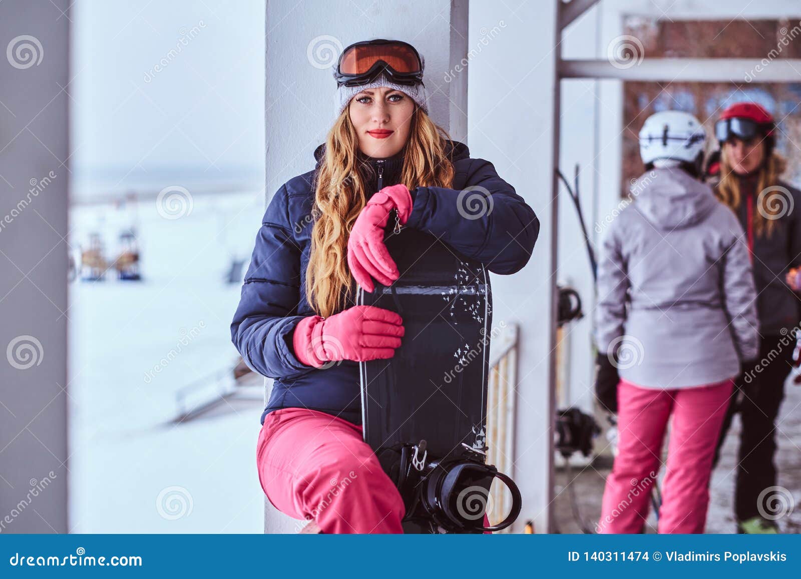 Ropa De Deportes Del Invierno La Mujer Que Lleva Rubia Que Presenta Con Una Snowboard de archivo - Imagen de amigos, activo: 140311474