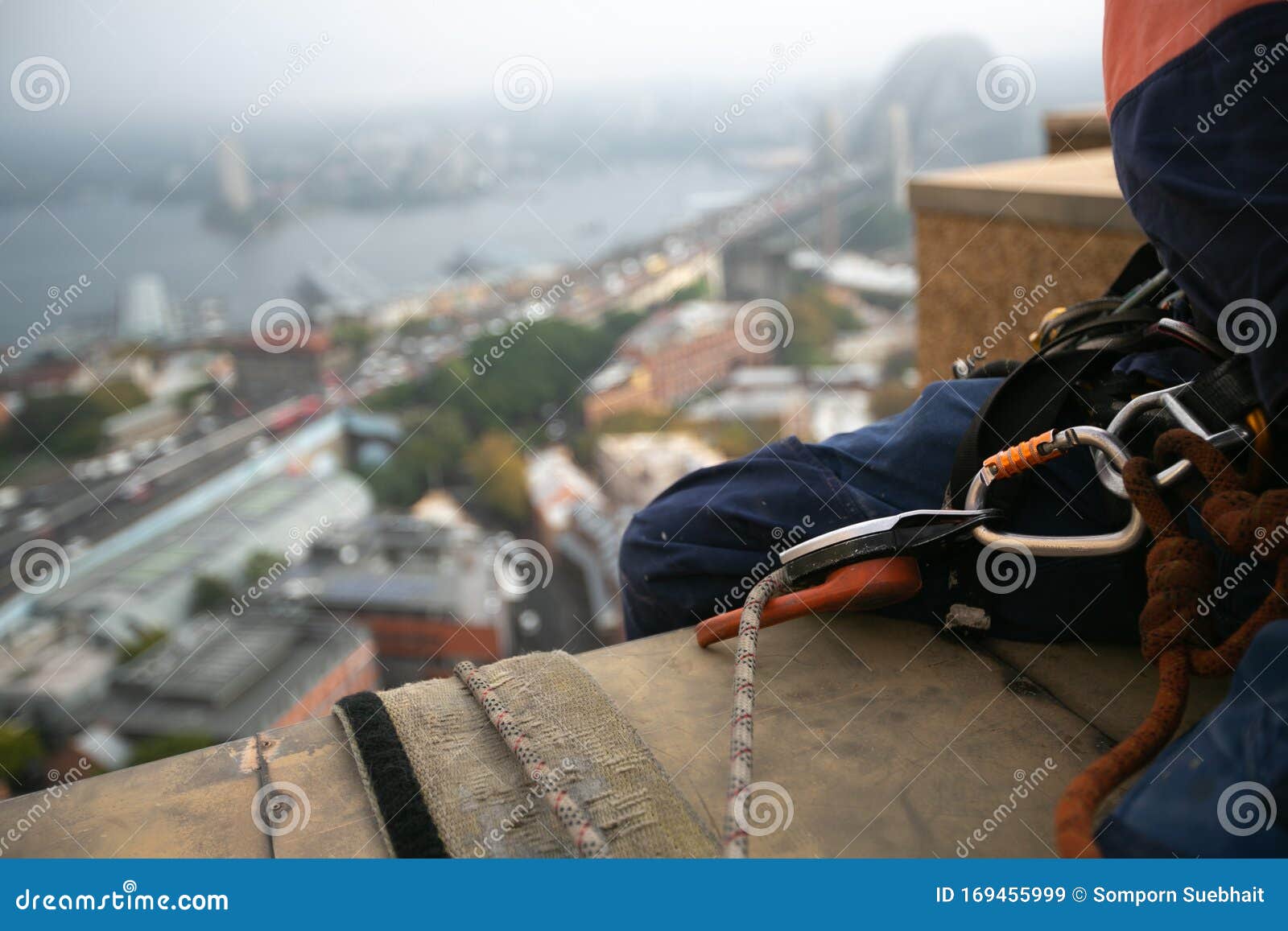 rope access abseiler sitting over high rise building edge having hardware descender device clipping on 10.5 mm dynamic low stretch
