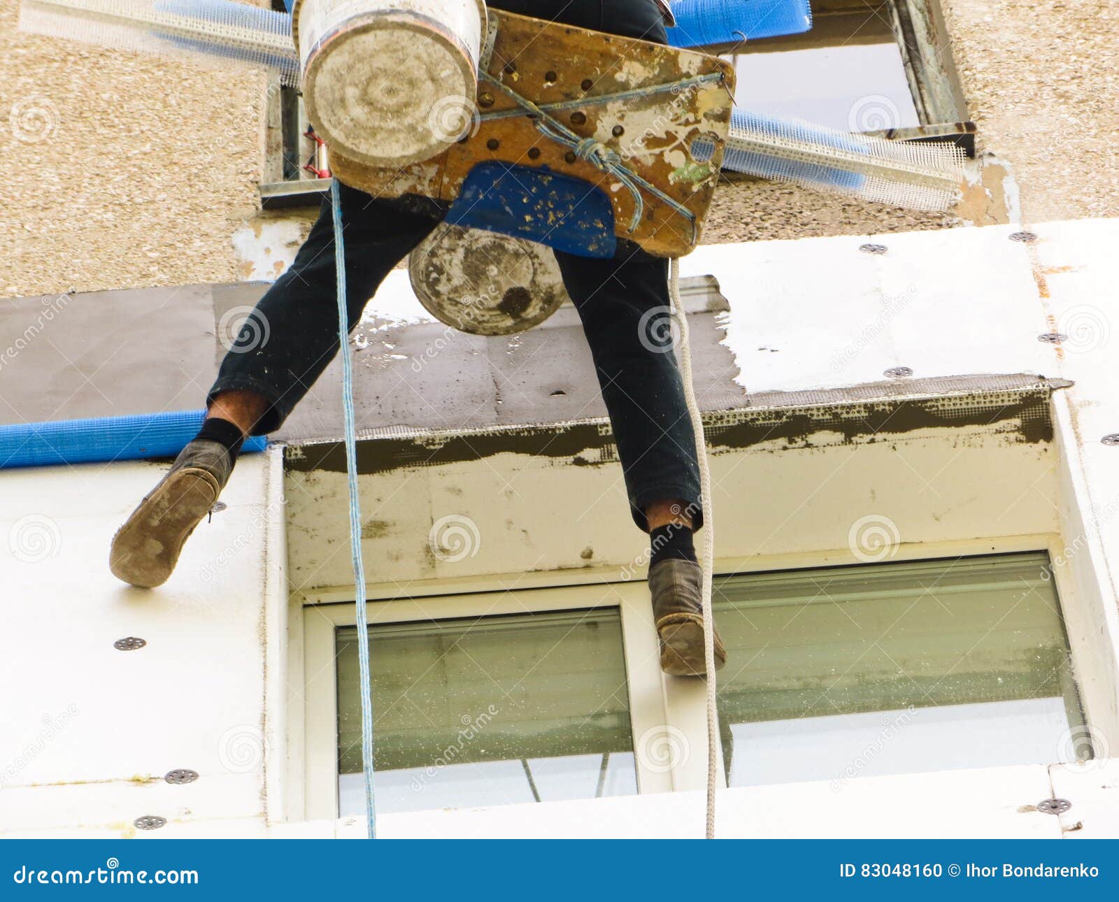Rope Access Worker Spreading Mortar Over Styrofoam Insulation Stock