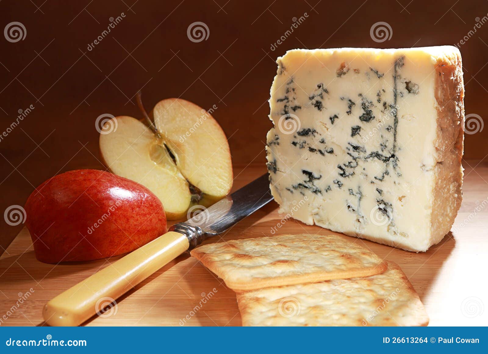 Roquefort retro. Uma cunha do queijo do Roquefort em uma placa com uma maçã da gala, uma faca e uns biscoitos reais do biscoito do creme