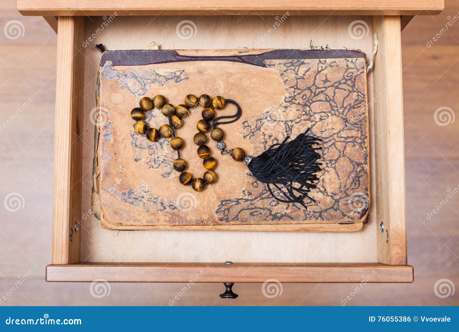 rosary on ansient book in open drawer