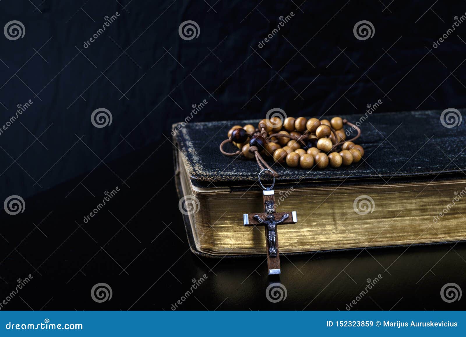 rosary beads and prayer book on dark background
