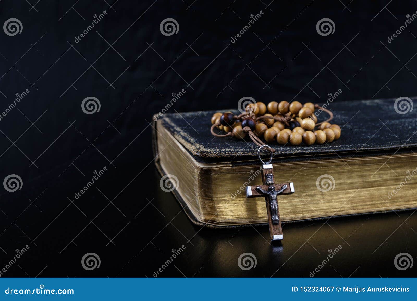 rosary beads and prayer book on dark background