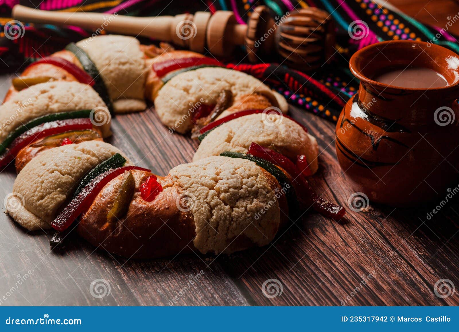 rosca de reyes or epiphany cake and clay mug of mexican hot chocolate on a wooden table in mexico latin america