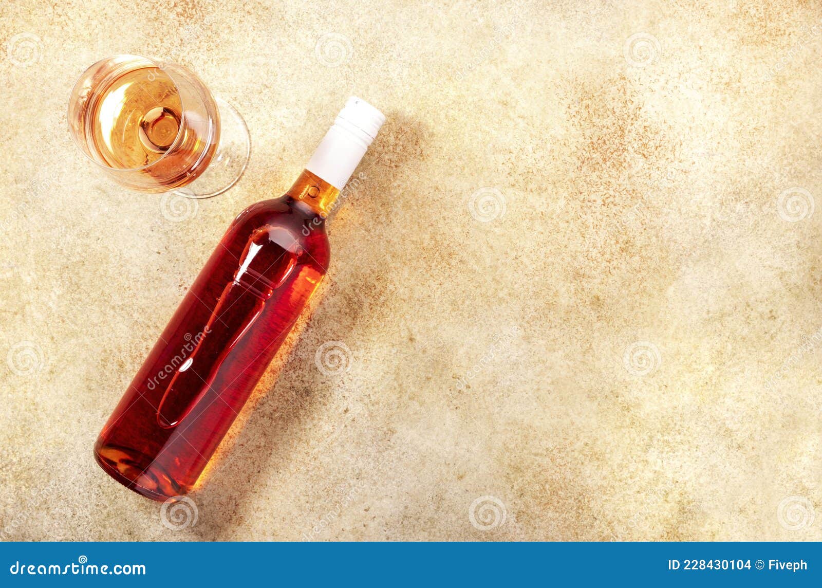 rose wine glass with bottle on the beige table. copy space, top view