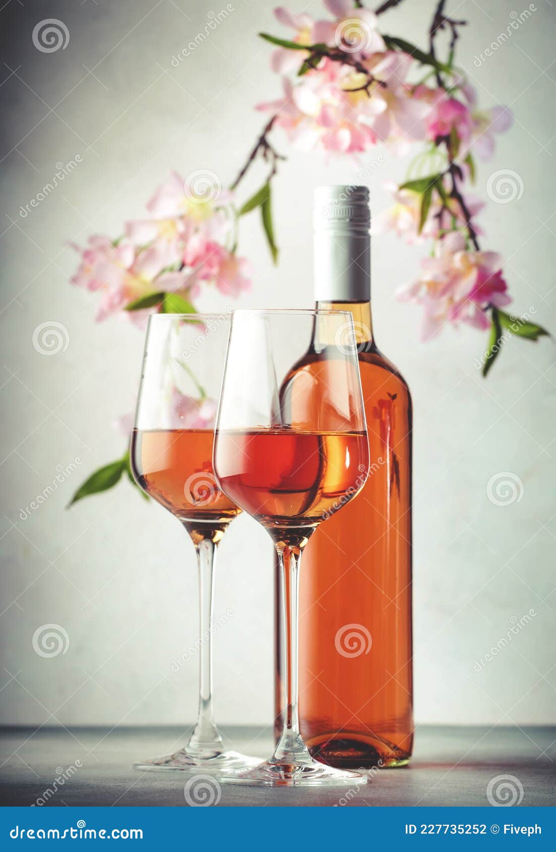 rose wine glass and bottle on the gray table and pink flowers. rosado, rosato or blush wine tasting