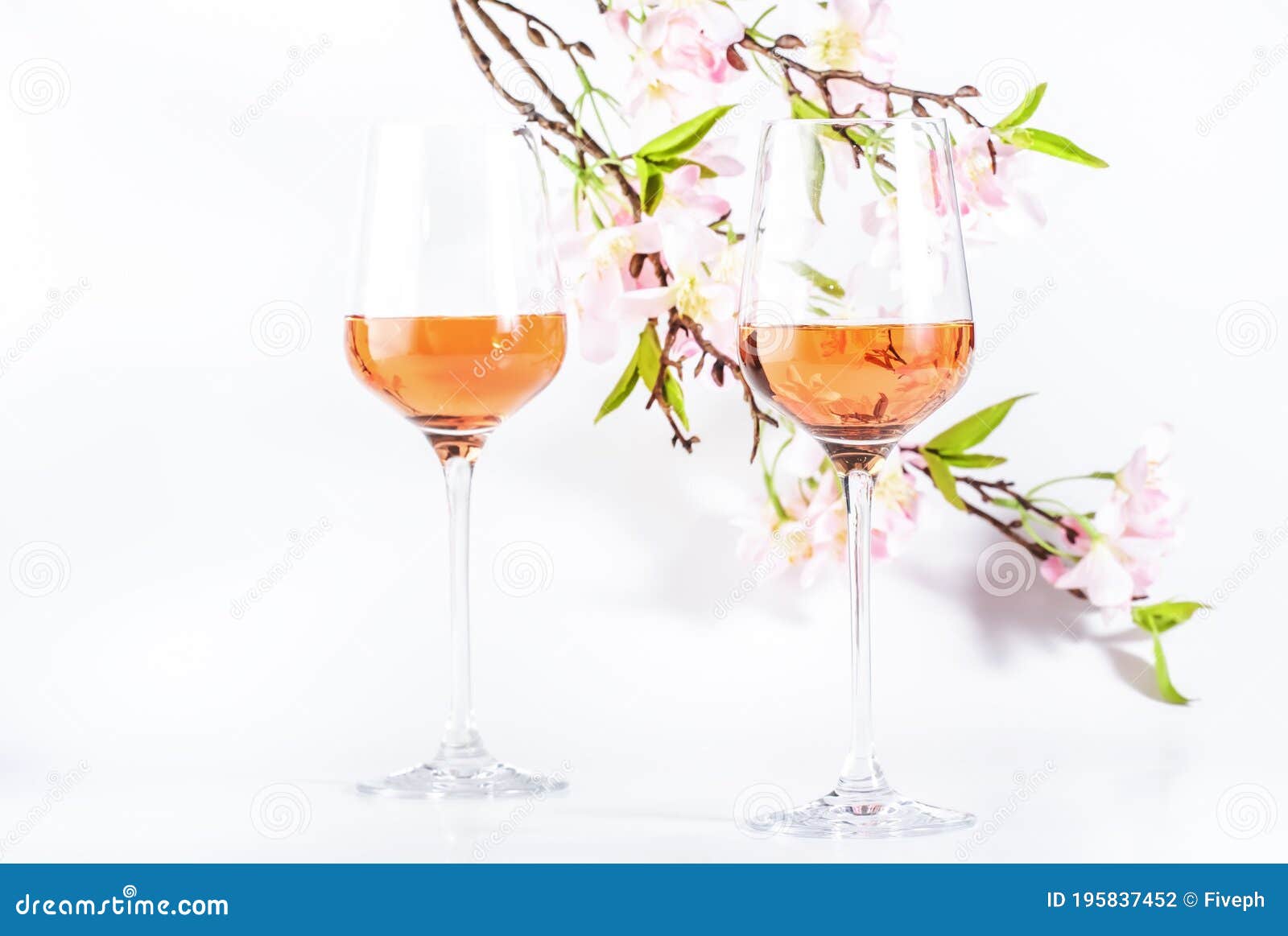 rose wine glass with bottle on the white table and pink flowers. rosado, rosato or blush wine tasting in wineshop, bar concept.