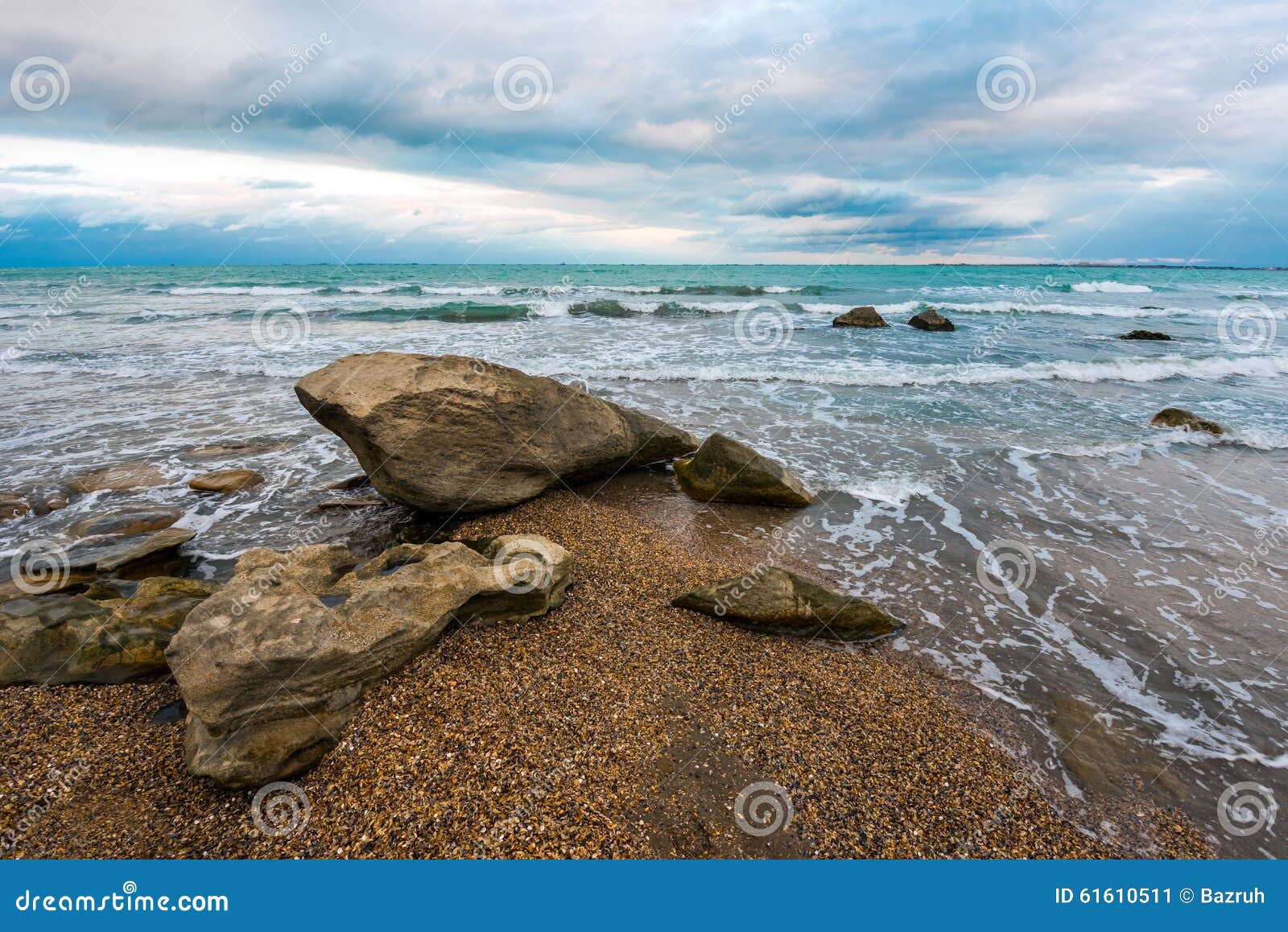 Rotsen op kust, leeg strand, koude. Zeegezicht, blauw water, wolken over overzees