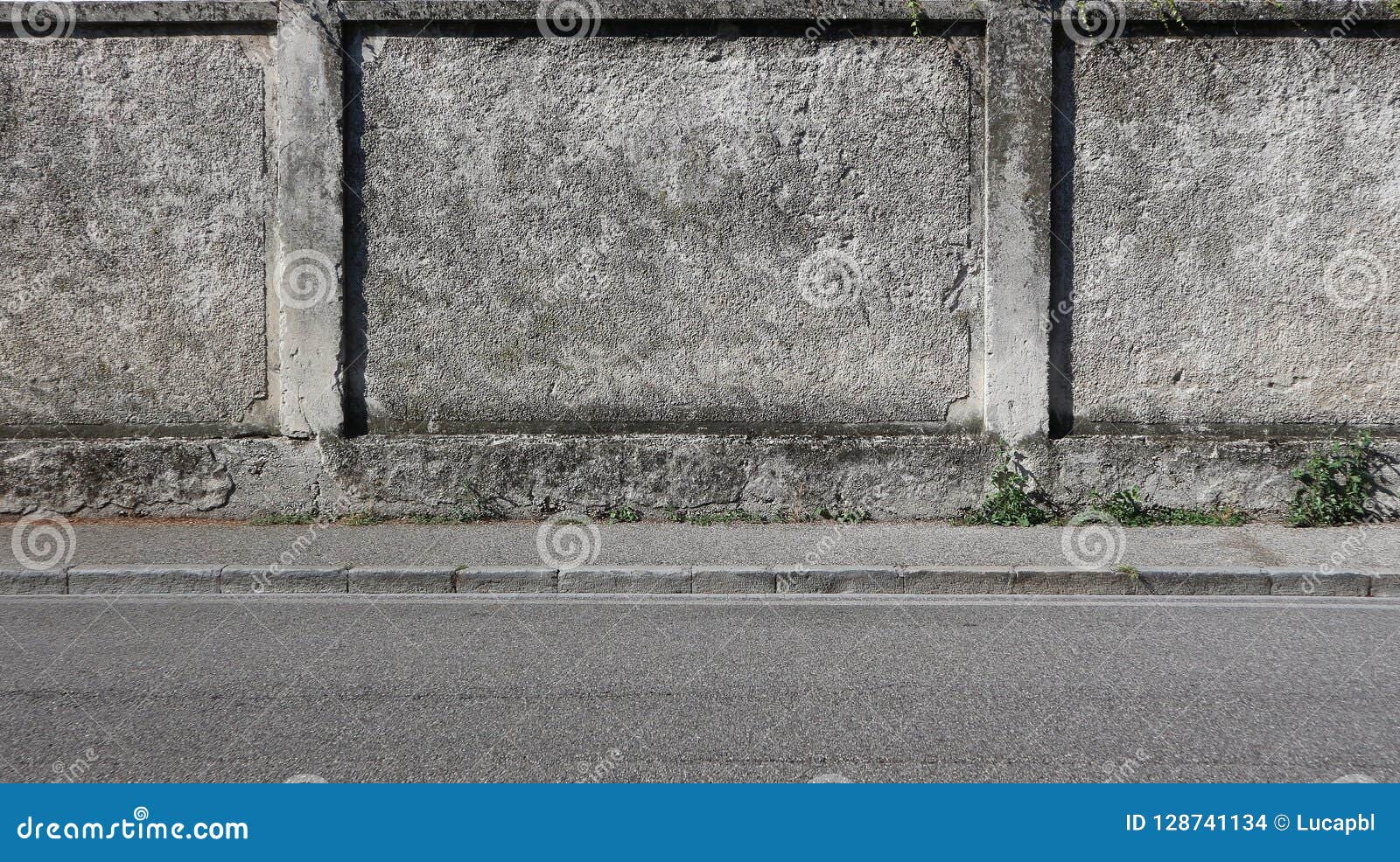 a rough concrete wall with a gray sidewalk and an asphalt road. urban background for copy space