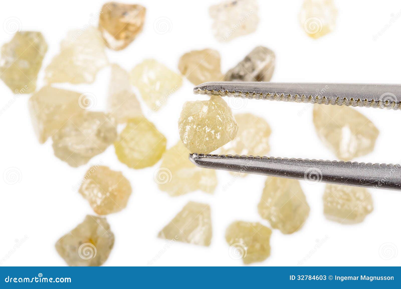 Rough uncut diamonds and tweezers. A pile of rough uncut and raw diamonds isolated on white. One is held by tweezers.