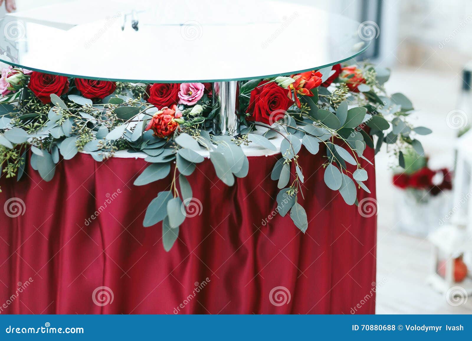 Round Glass Table with Red Cloth Decorated with Greenery Stock Photo