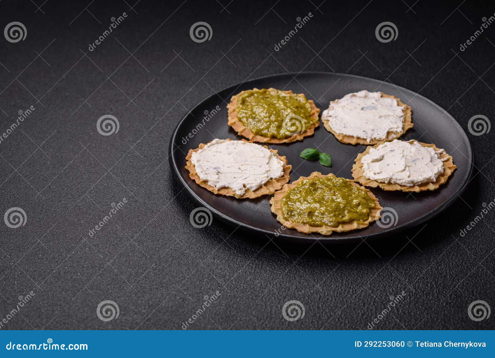 Round Snacks with Crispy Chips or Crackers with Cream Cheese and Pesto