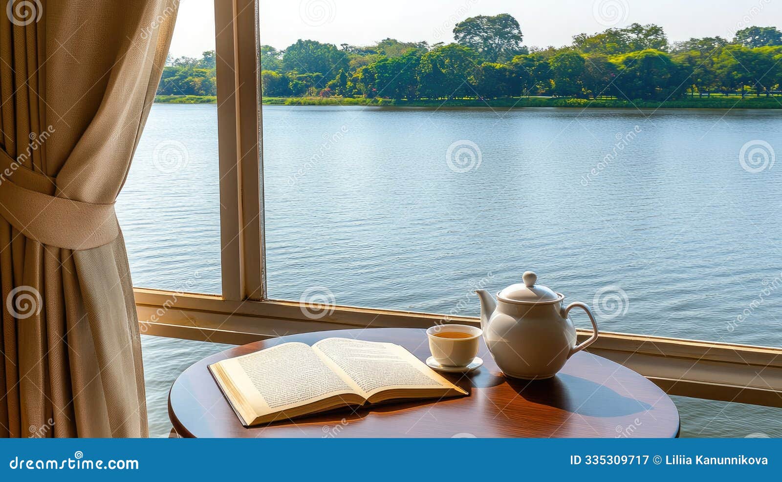 a round wooden table features a teapot and cup next to an open book while natural sunlight streams through light-colored