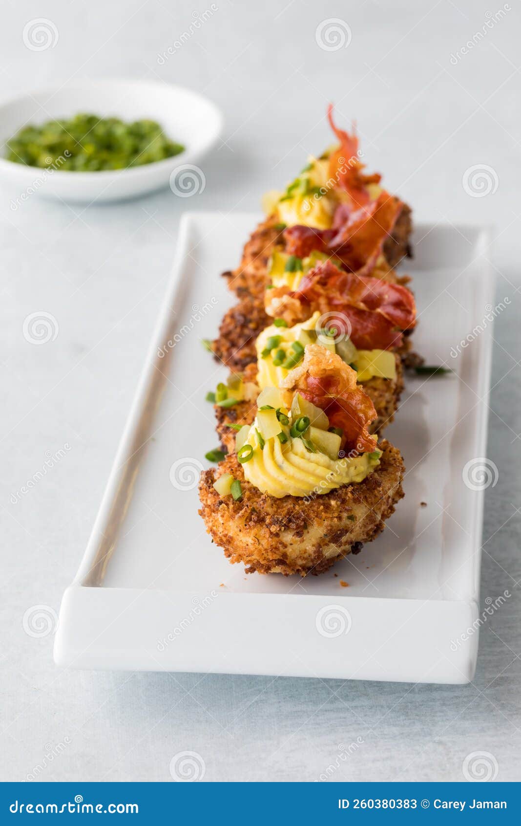 A Row of Deep Fried Gourmet Deviled Eggs Garnished with Chives and
