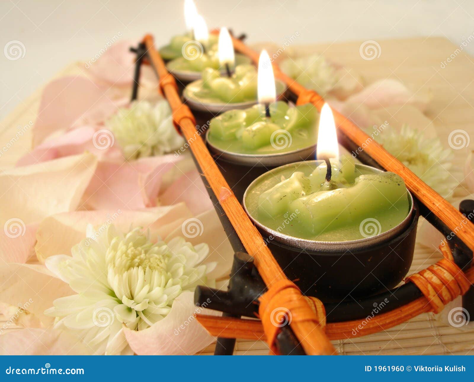 row of green candles over straw matt with rose petals