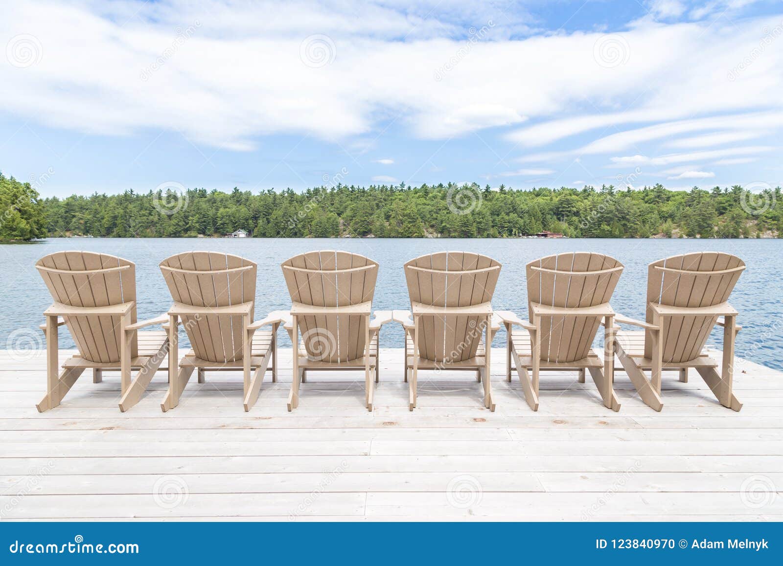 row of muskoka chairs on a dock looking onto the lake.