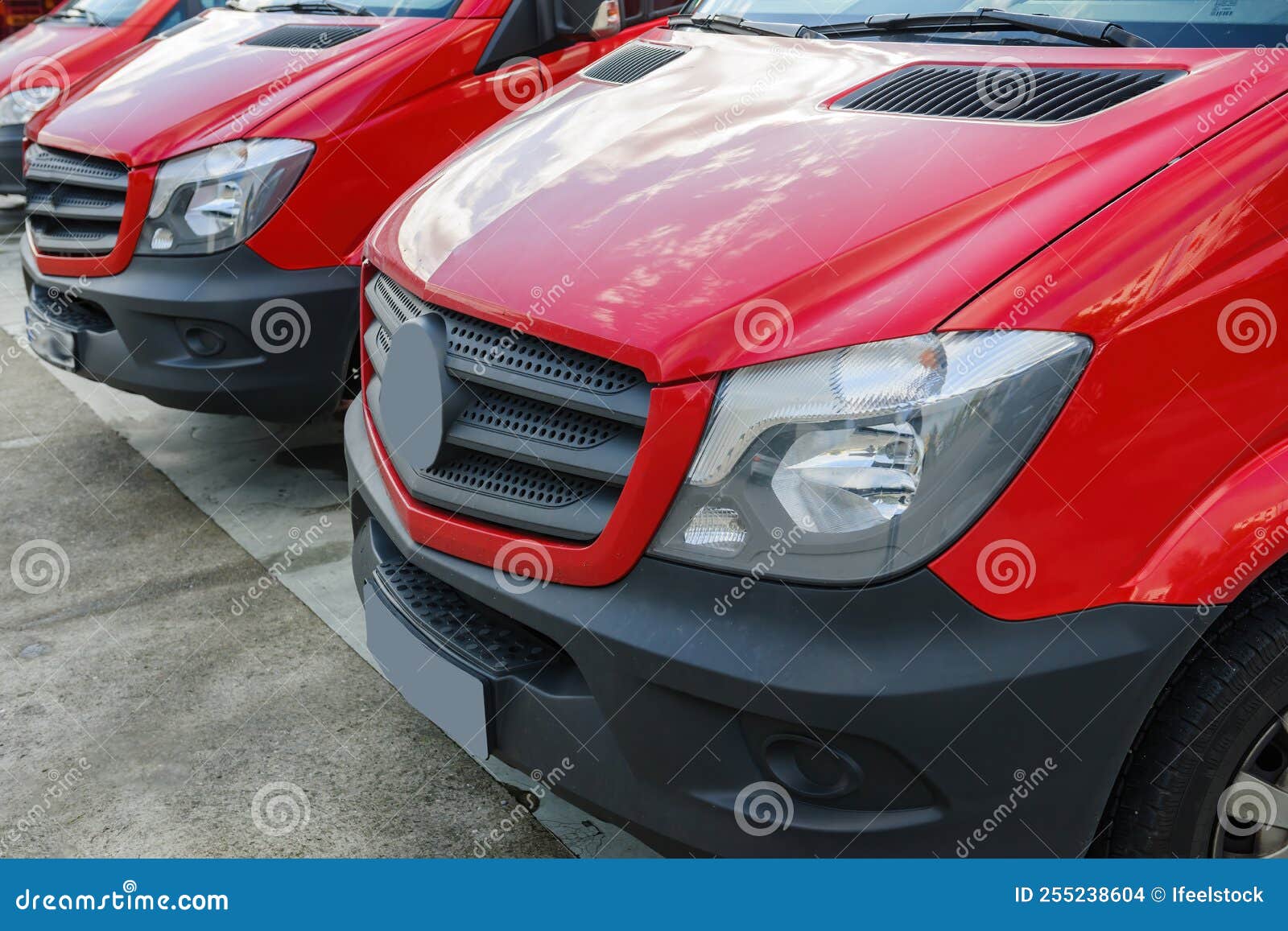 Row of Red Delivery Vans Parked in Front of Distribution Warehouse