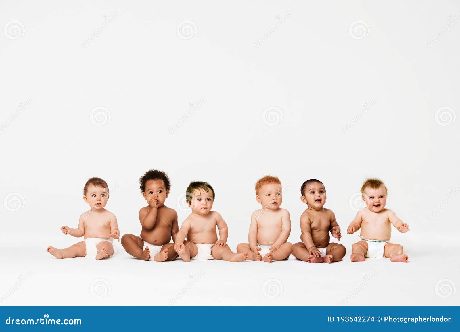 row of six multi ethnic babies smiling in studio