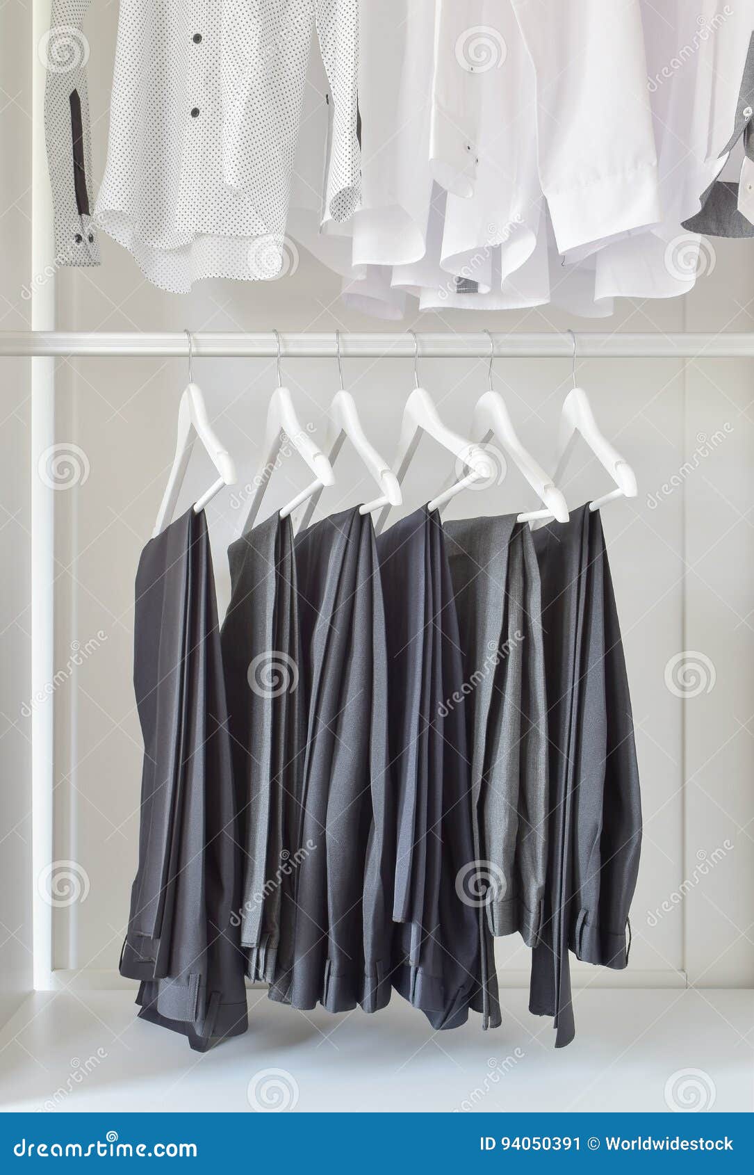 Row of White Shirts and Black Pants Hanging in Wooden Wardrobe Stock ...