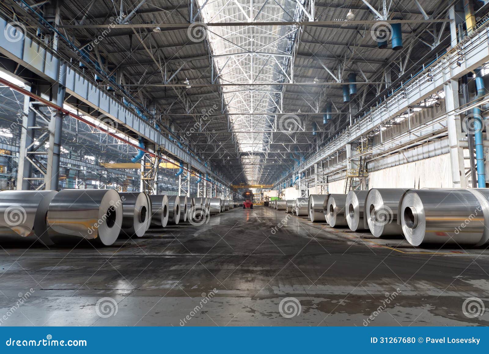 rows of rolls of aluminum lie in production shop