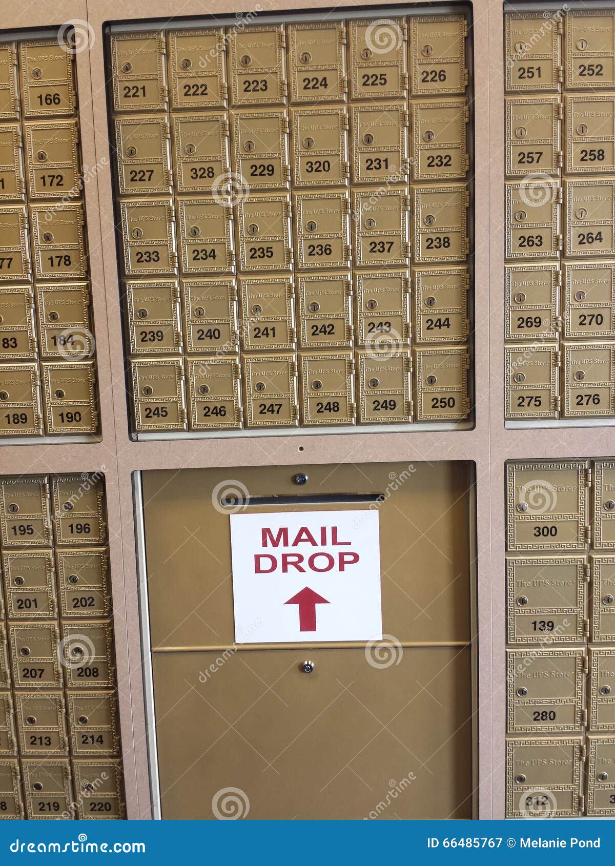 Rows of Small Metal Mailboxes Lined Against a Wall with a Letter Drop