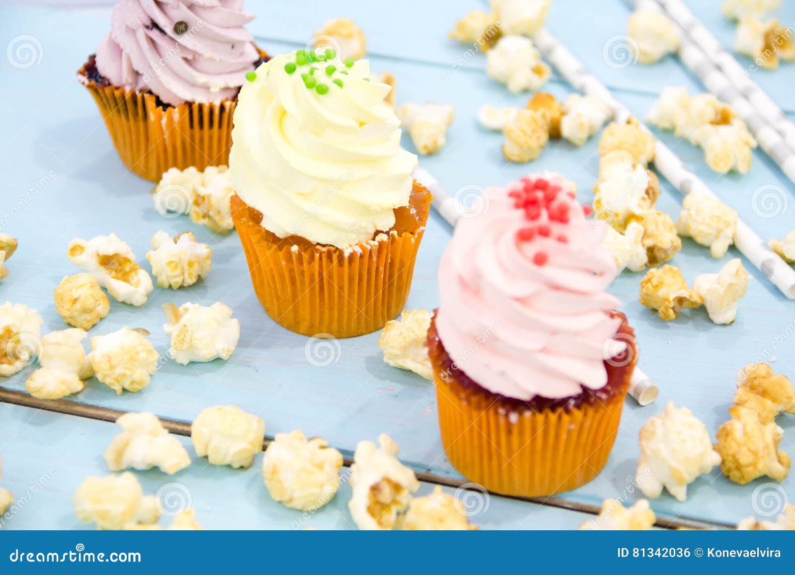 Roze cupcakes op lichtblauwe achtergrond wordt berijpt die. Cake, suikergoed, heemst, cakepops, vruchten en andere snoepjes op dessertlijst bij de partij van de jonge geitjesverjaardag