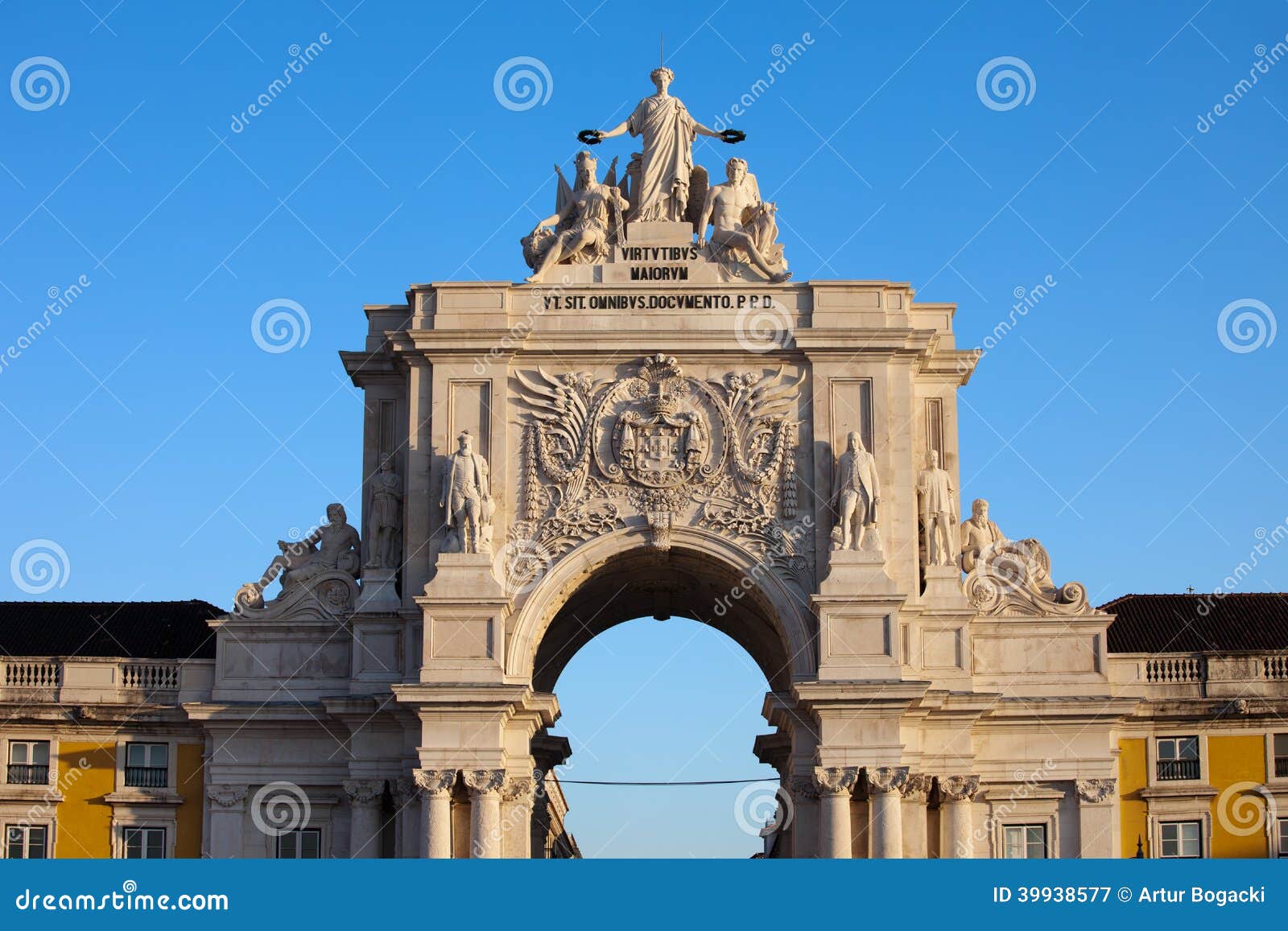 Rua Augusta Arch at sunrise in Lisbon, Portugal. Statues at the top: Allegory of Glory rewarding Valor and Genius, coat of arms of Portugal below.