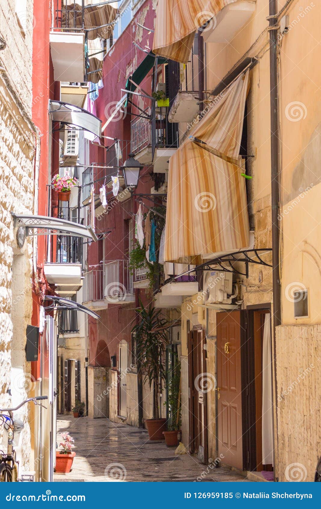 Rua italiana estreita com balcões, roupa de secagem e bicicleta Arquitetura mediterrânea tradicional Marco italiano da cidade Fundo do curso e das férias Conceito europeu das férias