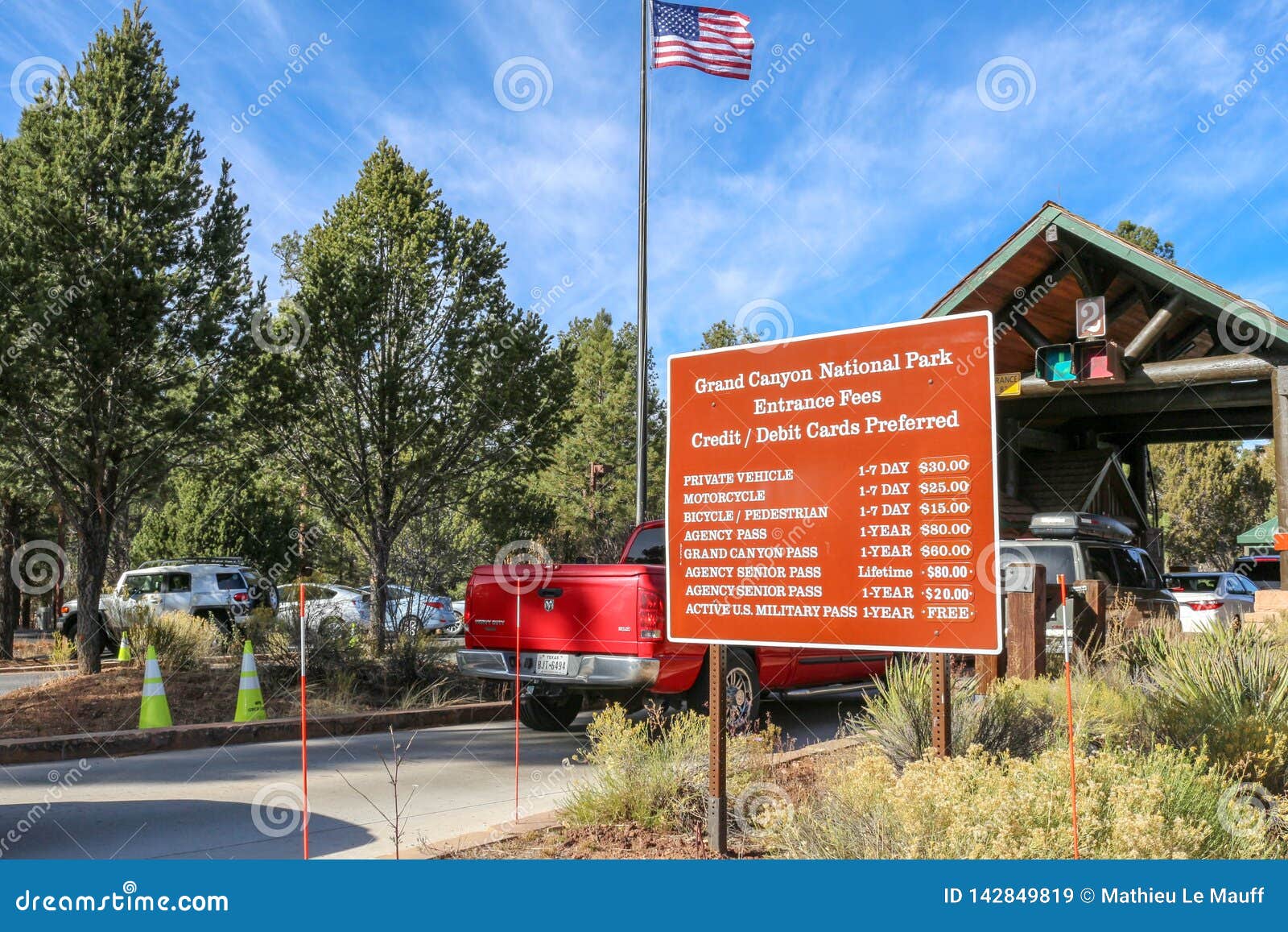 Ruch drogowy Przyjeżdża przy Grand Canyon parka narodowego obręcza opłaty drogowej Południowych Booths i Wejściowych opłat znakie. Widok samochody przyjeżdża przy Grand Canyon parka narodowego obręcza opłaty drogowej Południowymi booths, wejściowych opłat znak i USA, zaznaczamy w tle Fotografia brać na słonecznym dniu