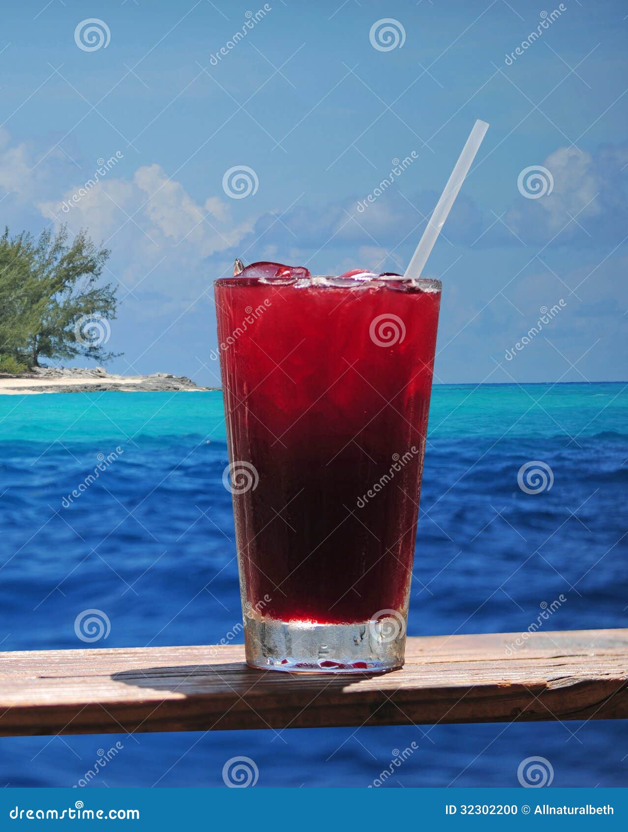 Rum punch or fruity drink in a tropical paradise with a turquoise ocean and clear blue water