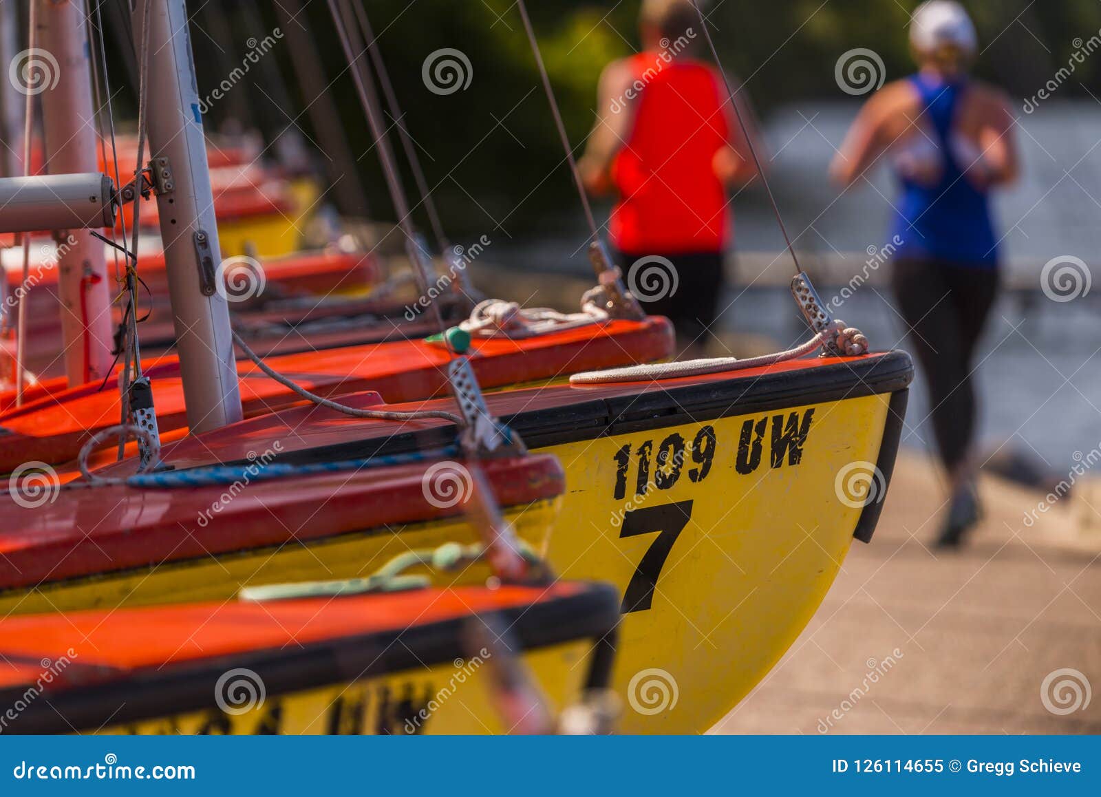 runners pass by sailboats along lake mendota, madison, wisconsin.