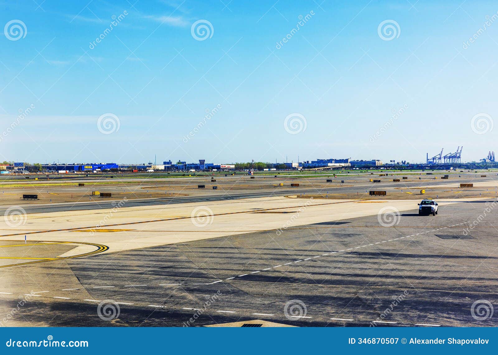 runway at newark liberty international airport with view of the ikea building, shipping cranes.