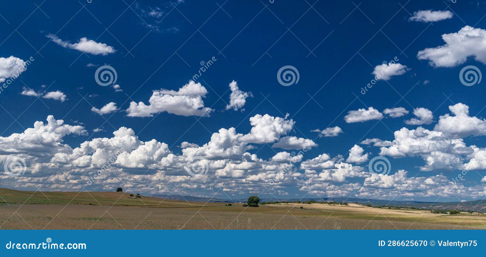 rural landscape of fields, hills and stunning skyscape with cumulus clouds