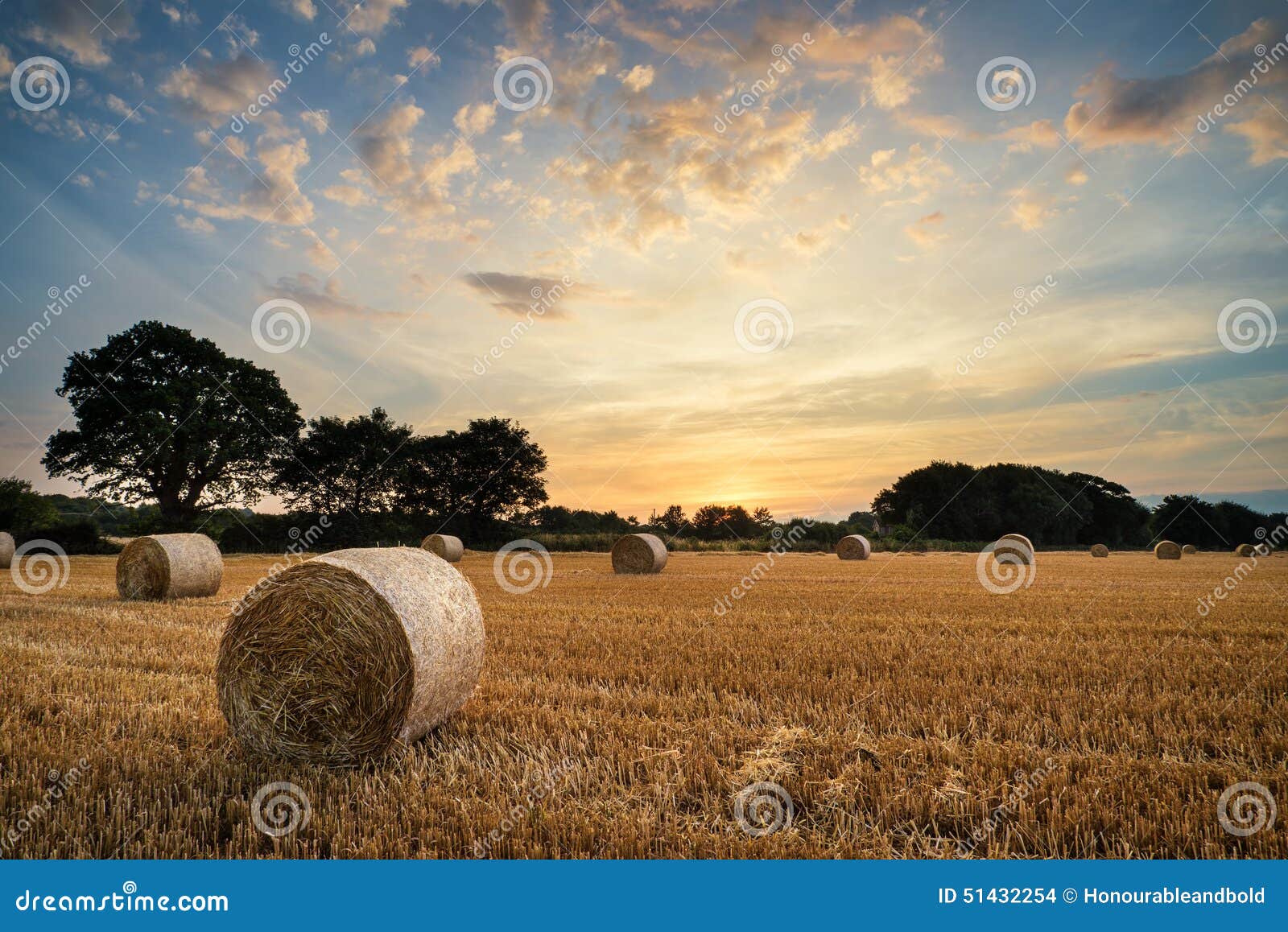 rural landscape image of summer sunset over field of hay bales