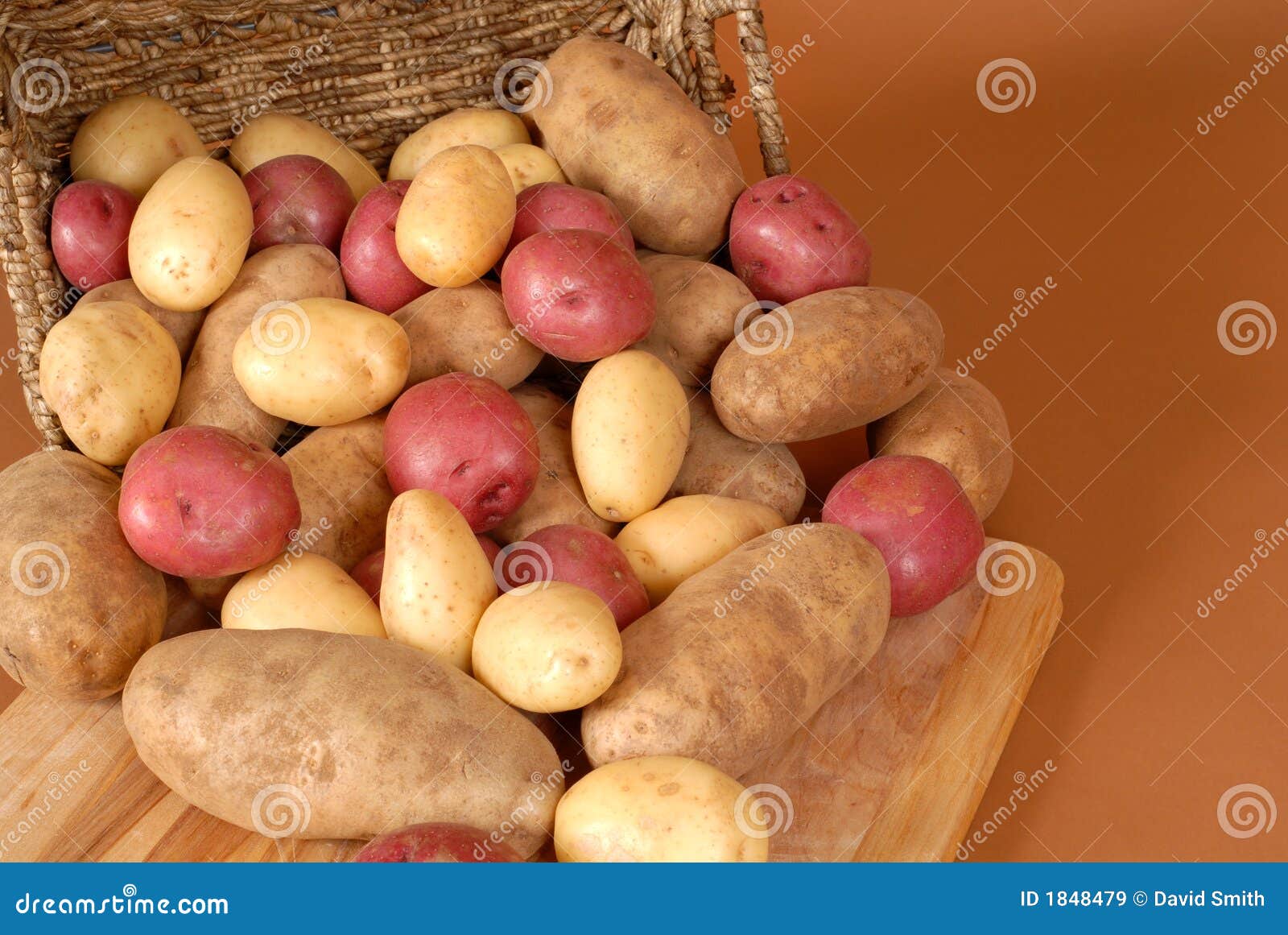 russet, red and white potatoes spilling out of a basket onto cut