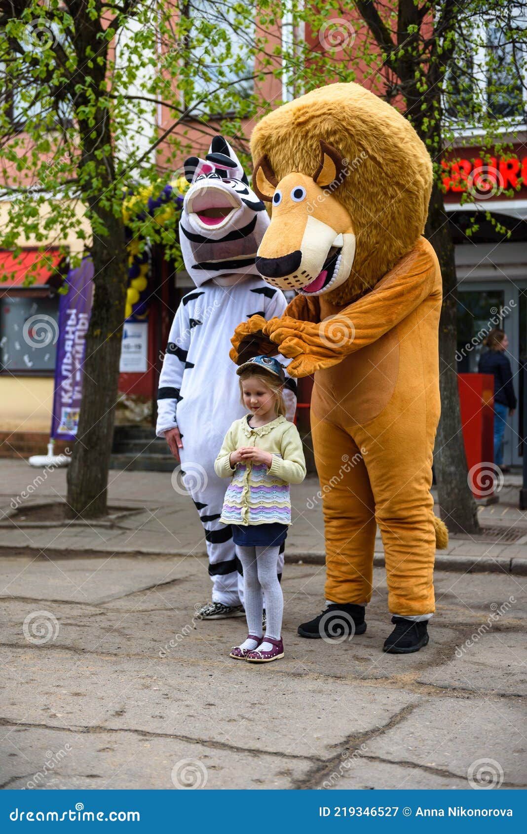 A Man in a Lion Costume on a City Street Embraces and Takes Photos with ...